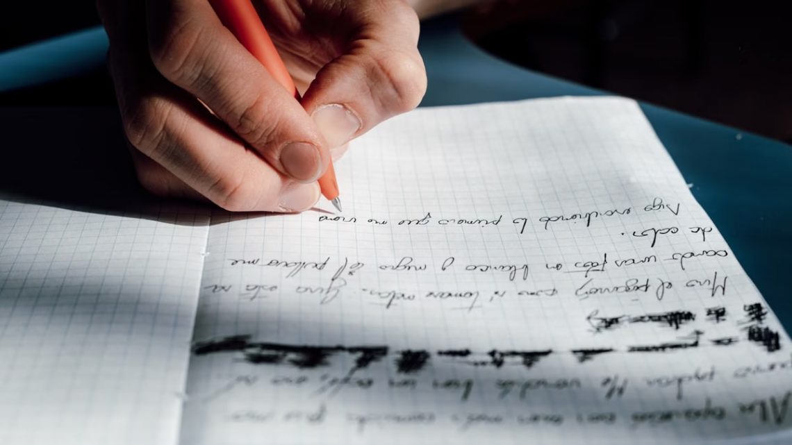 Close-up of a hand writing on a notepad, bathed in sunlight, indoors.