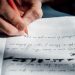 Close-up of a hand writing on a notepad, bathed in sunlight, indoors.